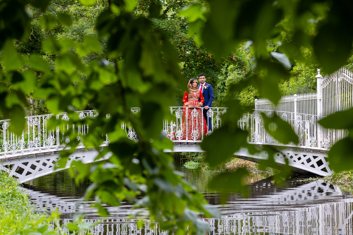 Asian couple standing on bridge at morden hall