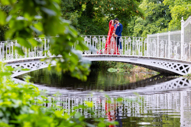 Bride and groom posing on the bridge at morden hall